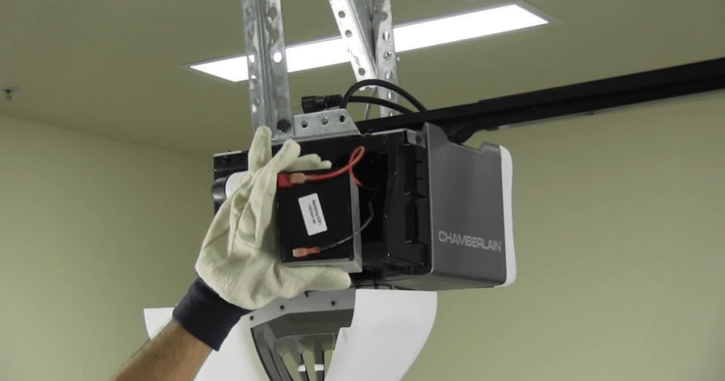Gloved hand installs battery in opener.