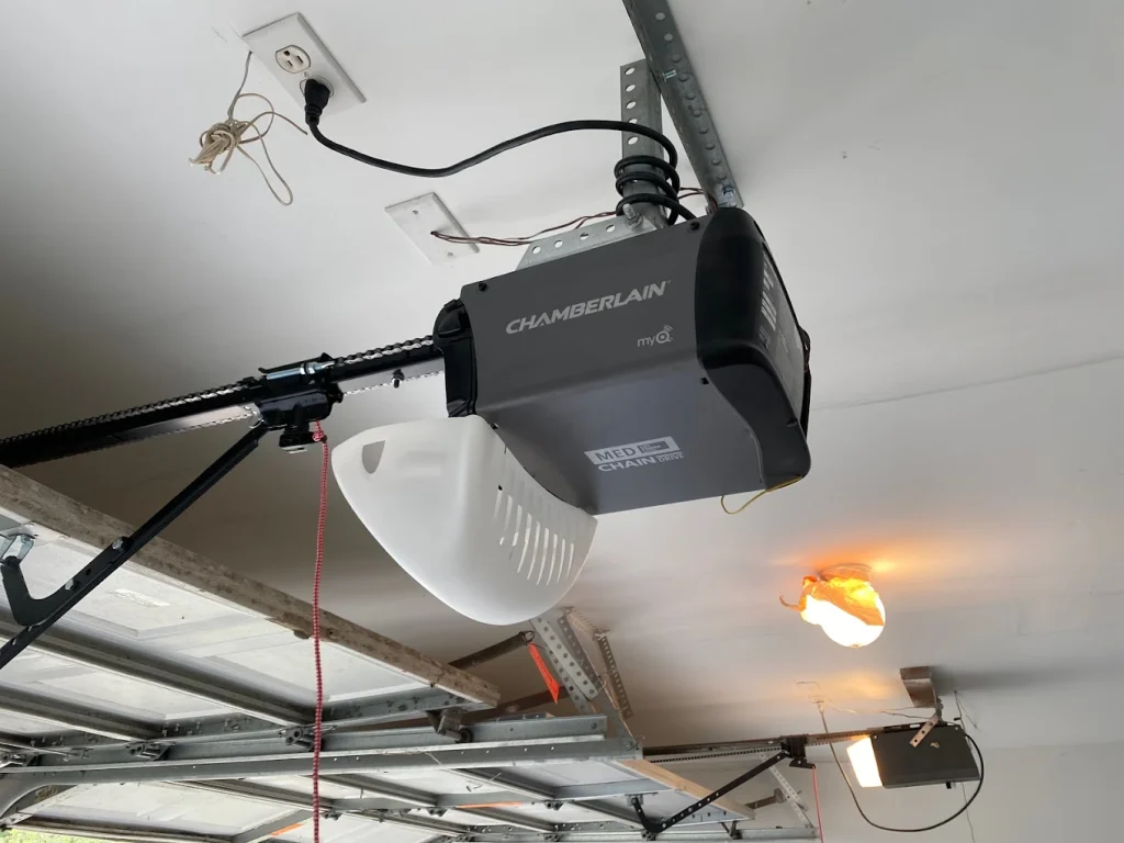 A ceiling-mounted Chamberlain overhead motor unit featuring a backup power compartment for Garage Door Opener Battery Replacement.